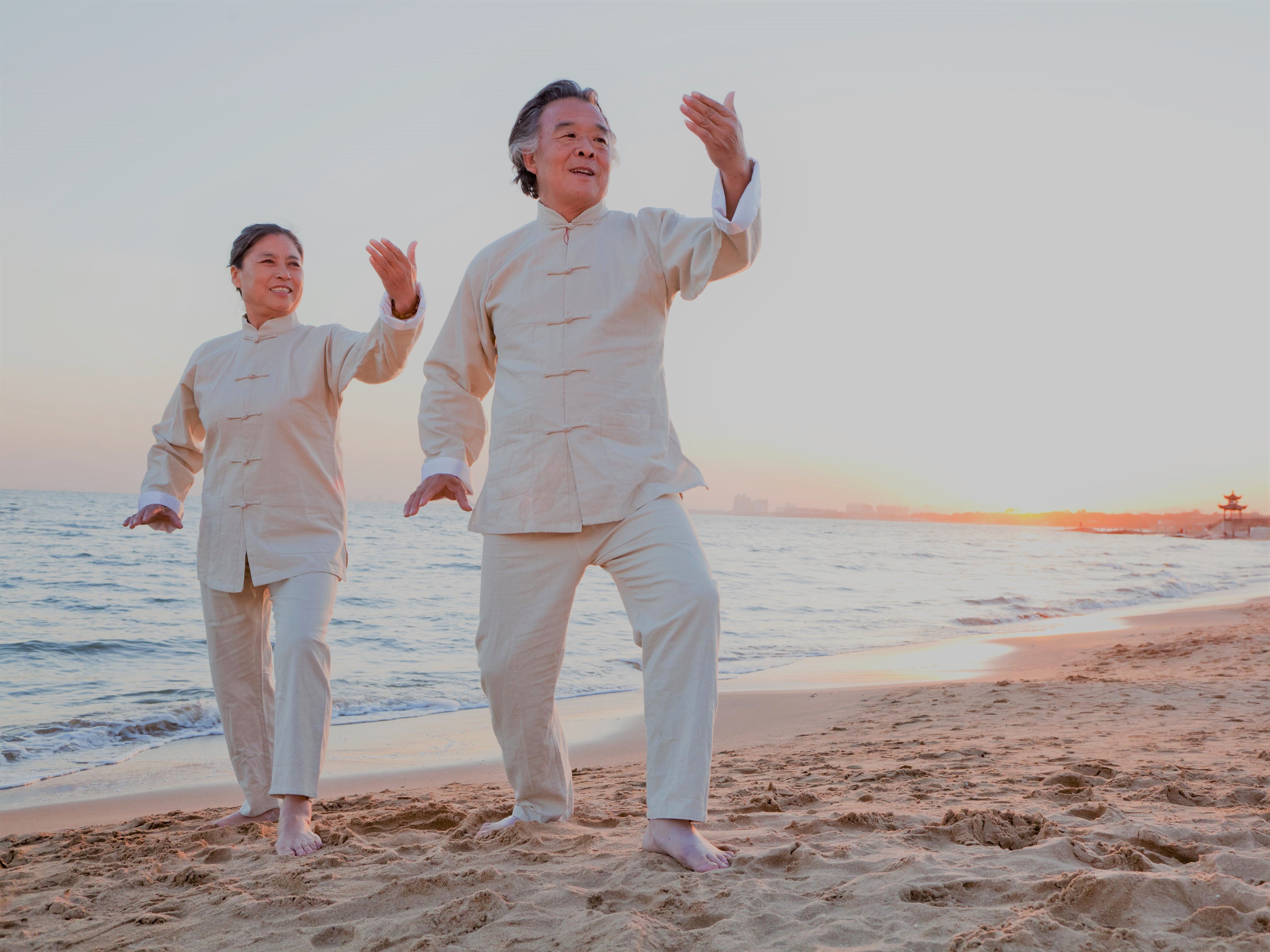 asian-elderly-couple-doing-taichi-at-beach