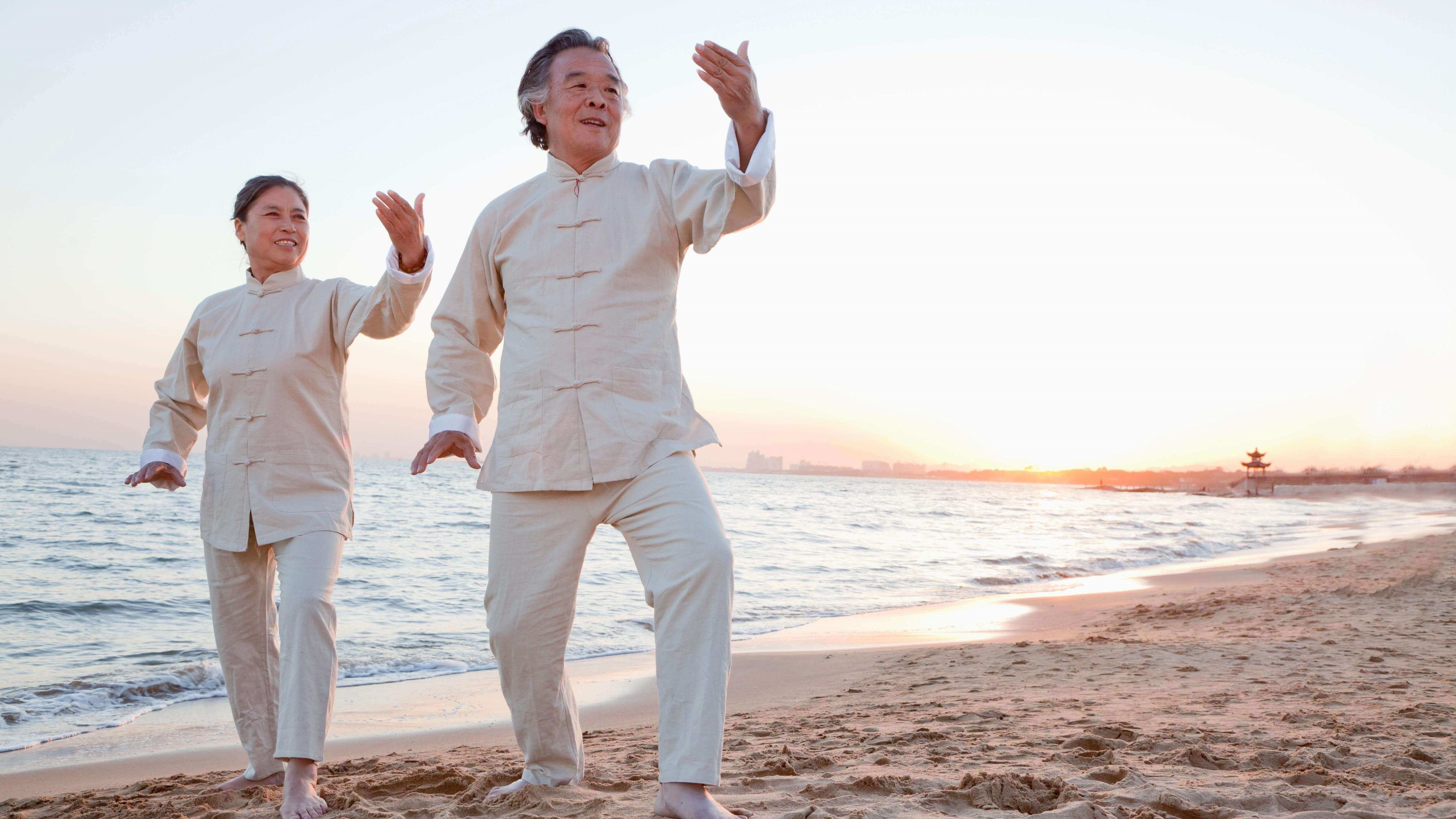 asian-elderly-couple-doing-taichi-at-the-beach
